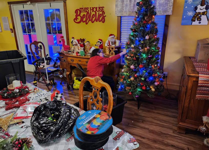 A resident in his recliner with a Christmas tree branch on his head, grinning