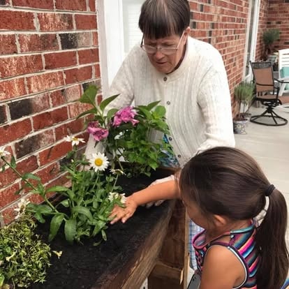 A resident and a young girl planting flowers together in a porch planter at Lavender Fields